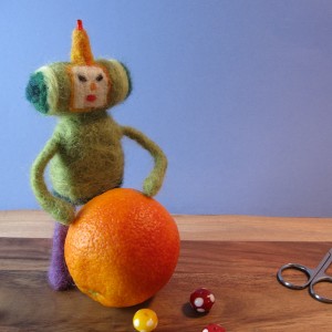 Needle-felted Prince of All Cosmos rolling an orange