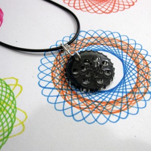 A Spirosketch necklace siting over a drawing made with spirosketch